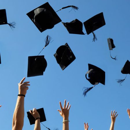 Graduation Caps Thrown in the Air on blue sky.