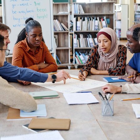 Group of multi-ethnic immigrant students attending international school lessons working on English language poster together