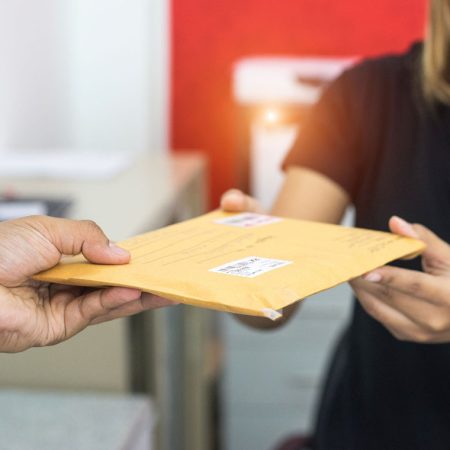 male hand send mail envelope to the female of post office before sending