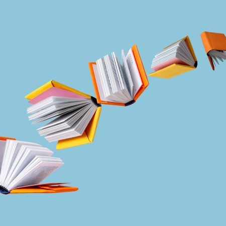 books in colored covers swirl on a blue background, copy space