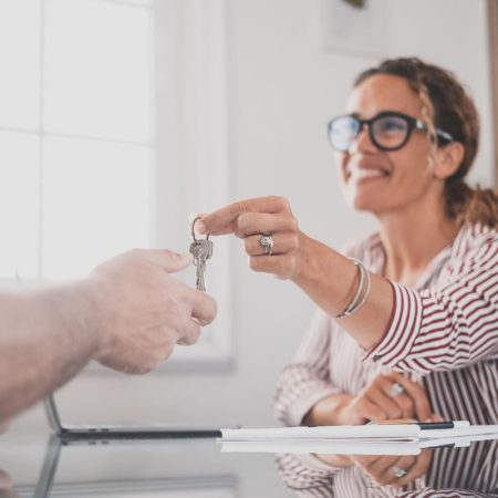 Crop close up of realtor give keys to man buyer or renter buying first home from agency. Real estate agent or broker congratulate male tenant with house or flat purchase. Ownership, rental concept.